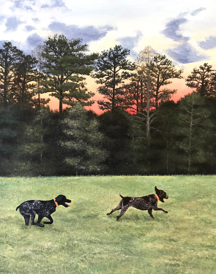 A painted outdoor scene showing two dogs running across a grassy field with a dark tree line and a cloudy sky at sunset. The artwork itself appears to be the product being shown, so this fits Scenery rather than Lifestyle.